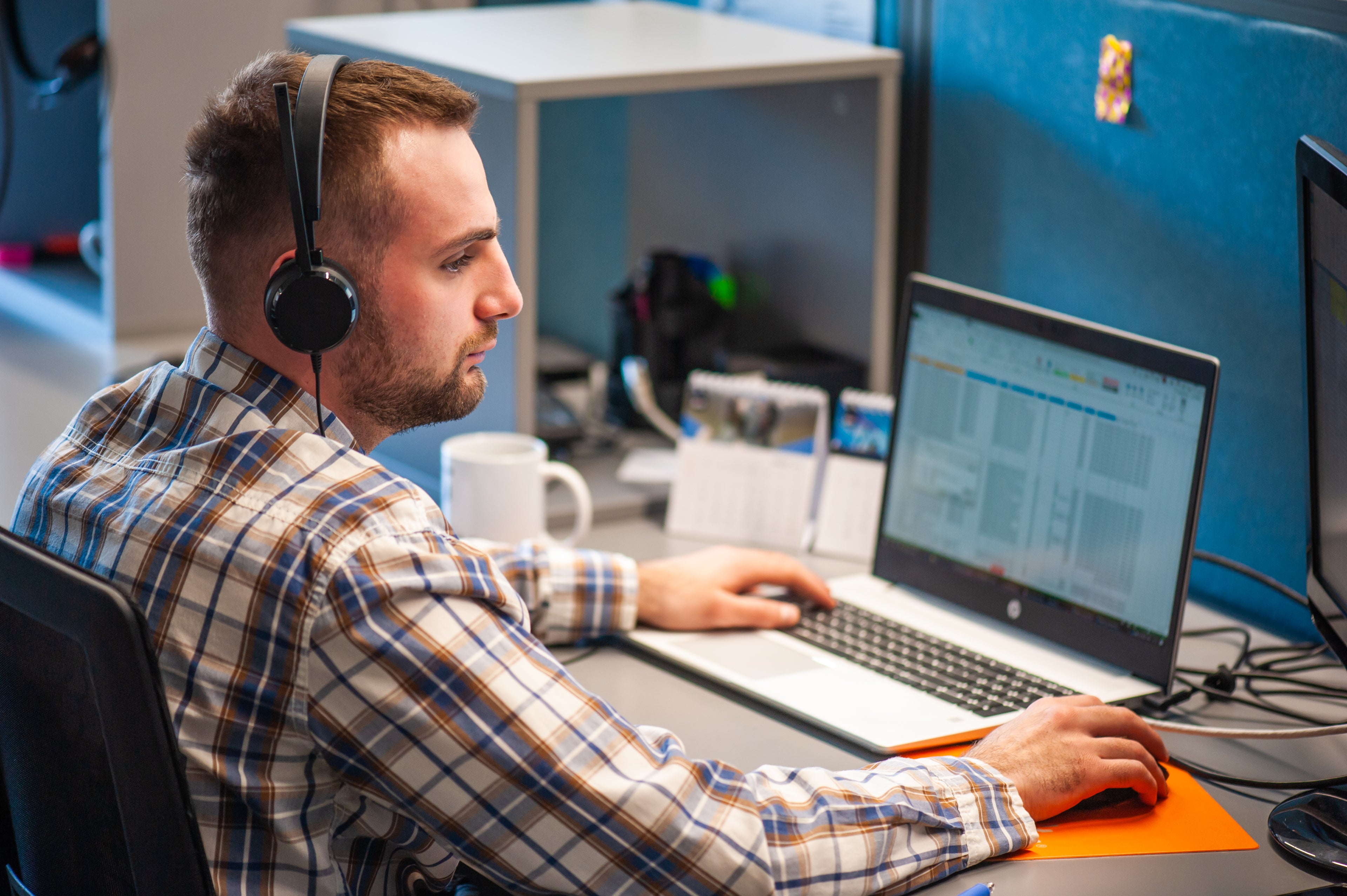 Support member working at a desk with headphones on, using a laptop.